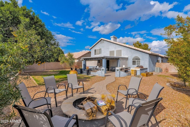 view of patio featuring cooling unit, exterior kitchen, and an outdoor living space with a fire pit