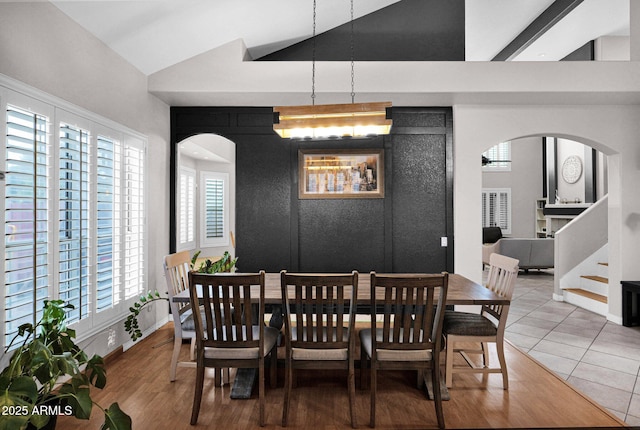 dining area with tile patterned flooring, a wealth of natural light, and vaulted ceiling