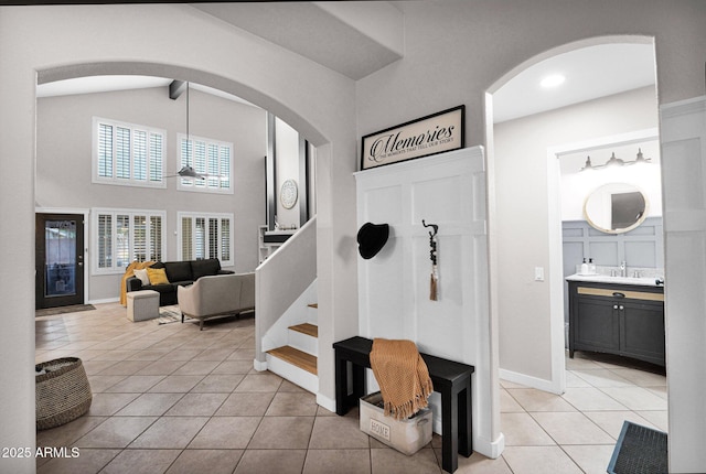 entrance foyer with light tile patterned flooring, lofted ceiling, and sink