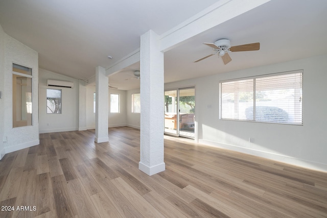 unfurnished living room with vaulted ceiling, light hardwood / wood-style flooring, ceiling fan, and an AC wall unit