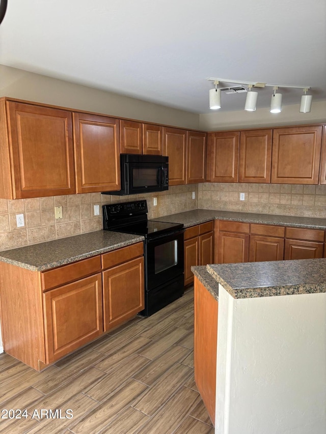 kitchen with tasteful backsplash, black appliances, and light wood-type flooring