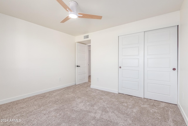 unfurnished bedroom featuring light carpet, a closet, and ceiling fan