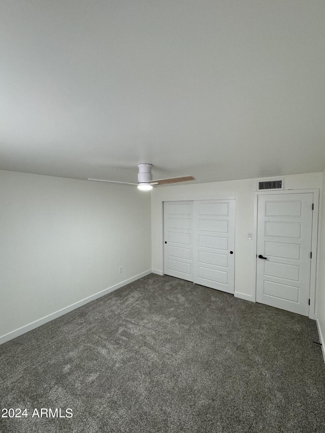 unfurnished bedroom with ceiling fan and dark colored carpet