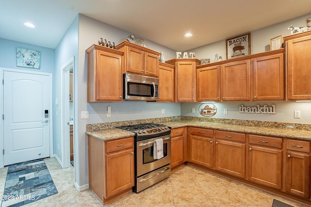 kitchen with appliances with stainless steel finishes and light stone counters