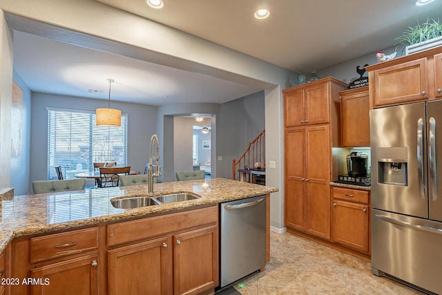 kitchen with pendant lighting, sink, ceiling fan, stainless steel appliances, and light stone counters