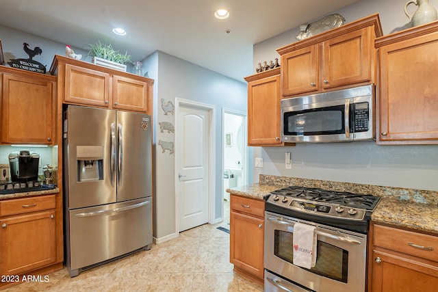 kitchen featuring light tile patterned floors, stone counters, and appliances with stainless steel finishes