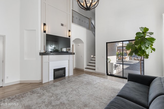 2533 W Novak Way, Phoenix, AZ 85041 - living room featuring a high ceiling, wood finished floors, arched walkways, stairs, and a large fireplace