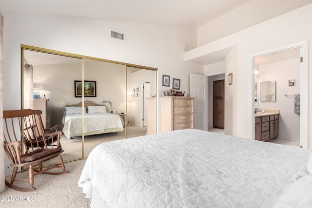 carpeted bedroom featuring ensuite bath, a closet, and lofted ceiling