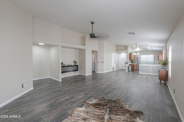 unfurnished living room featuring vaulted ceiling, ceiling fan with notable chandelier, and dark wood-type flooring