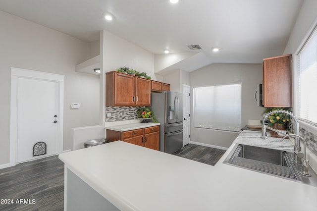 kitchen with stainless steel refrigerator with ice dispenser, kitchen peninsula, vaulted ceiling, backsplash, and dark hardwood / wood-style flooring