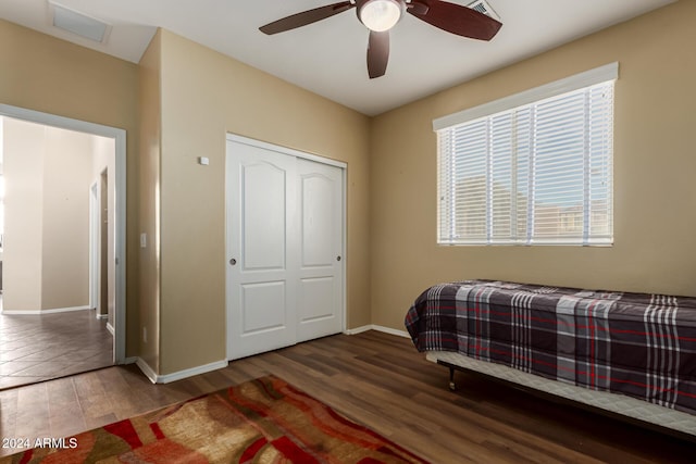 bedroom featuring a closet, ceiling fan, dark hardwood / wood-style flooring, and multiple windows