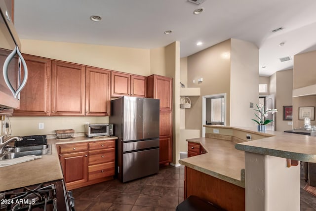 kitchen featuring a kitchen bar, stainless steel fridge, dark tile patterned floors, sink, and high vaulted ceiling