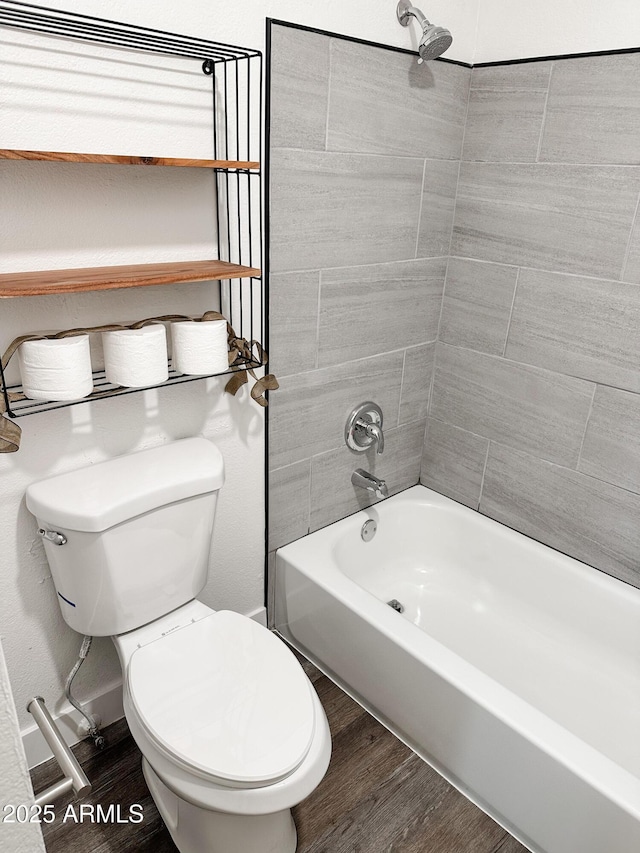 bathroom with toilet,  shower combination, and wood finished floors