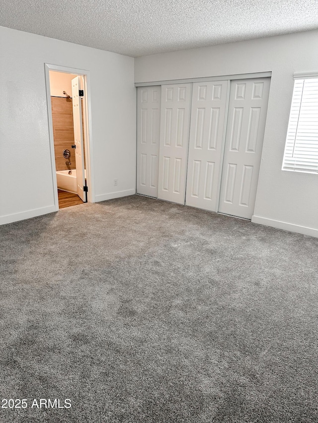 unfurnished bedroom featuring carpet flooring, a textured ceiling, and baseboards