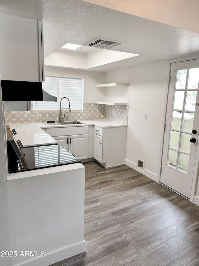 kitchen featuring visible vents, decorative backsplash, a healthy amount of sunlight, light wood-style floors, and a sink