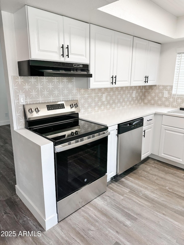 kitchen featuring light countertops, appliances with stainless steel finishes, light wood-style floors, and under cabinet range hood