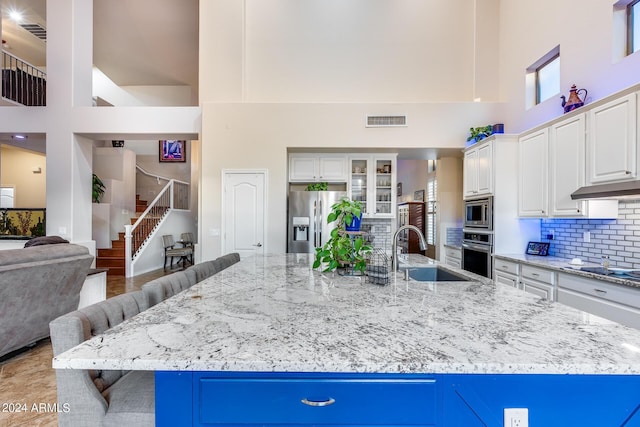 2728 W Adventure Dr, Anthem, AZ 85086 - kitchen featuring appliances with stainless steel finishes, a high ceiling, a kitchen bar, backsplash, and light stone counters