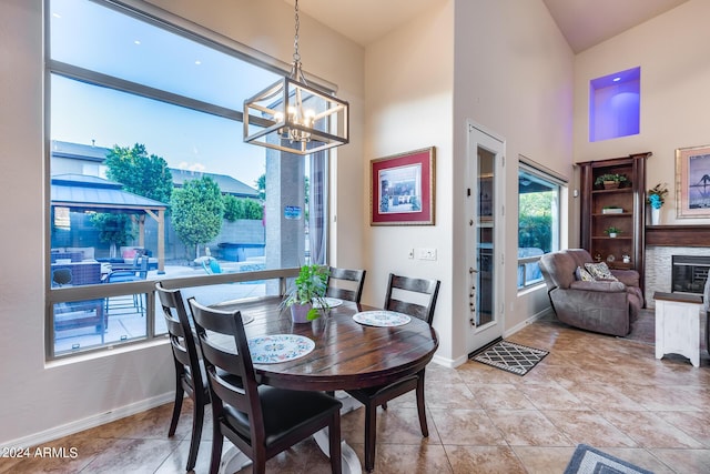 2728 W Adventure Dr, Anthem, AZ 85086 - dining space with a chandelier, a towering ceiling, a glass covered fireplace, and light tile patterned floors