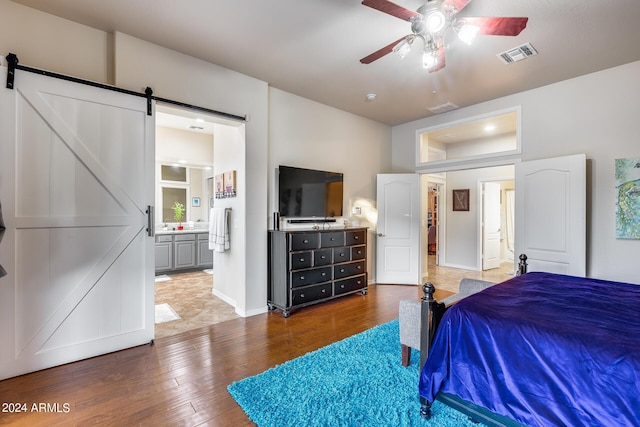 2728 W Adventure Dr, Anthem, AZ 85086 - bedroom with a barn door, hardwood / wood-style floors, ensuite bath, and ceiling fan