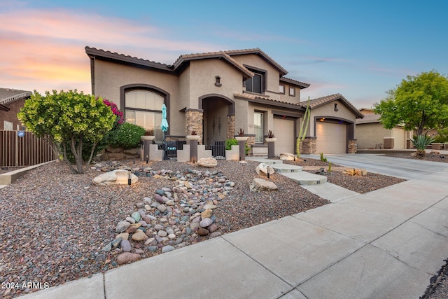 2728 W Adventure Dr, Anthem, AZ 85086 - mediterranean / spanish-style home with stucco siding, a tiled roof, driveway, stone siding, and a garage