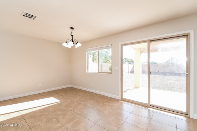 spare room with an inviting chandelier and light tile patterned floors