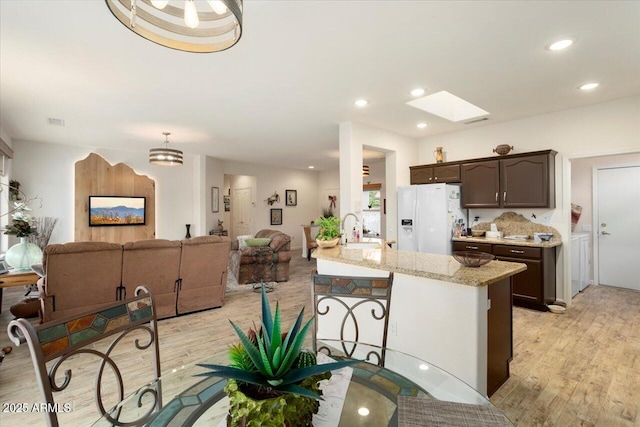 kitchen with light hardwood / wood-style floors, white refrigerator with ice dispenser, sink, and dark brown cabinets