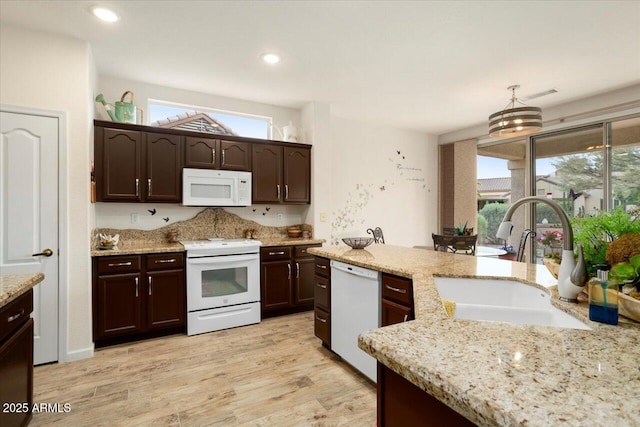 kitchen with sink, dark brown cabinets, light hardwood / wood-style flooring, pendant lighting, and white appliances