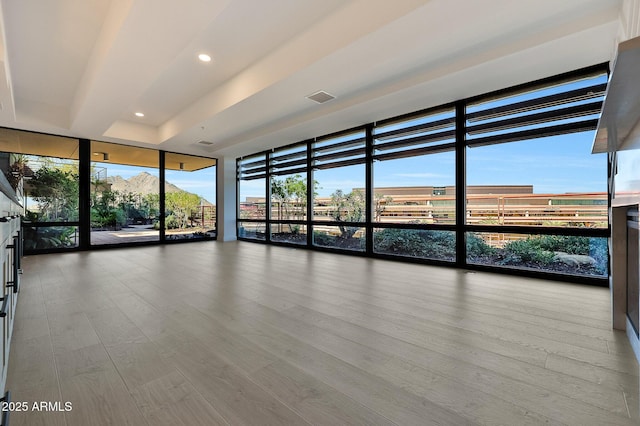 spare room with expansive windows, visible vents, wood finished floors, and recessed lighting