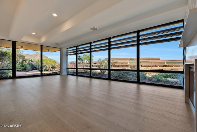 unfurnished room with expansive windows, visible vents, wood finished floors, and recessed lighting