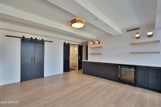 bar featuring visible vents, a barn door, light wood-type flooring, beamed ceiling, and baseboards