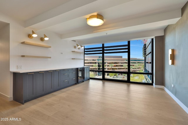 interior space featuring open shelves, a wall of windows, light wood-type flooring, and baseboards