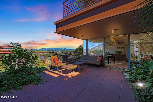 patio terrace at dusk featuring a mountain view, a balcony, and an outdoor hangout area