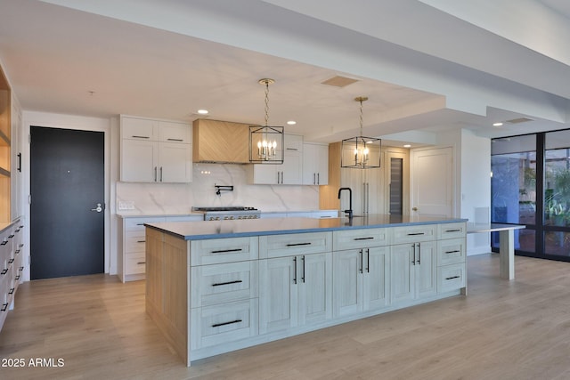 kitchen featuring white cabinets, a large island, tasteful backsplash, and light wood-style flooring