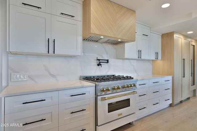 kitchen featuring decorative backsplash, gas stove, custom exhaust hood, and light stone countertops