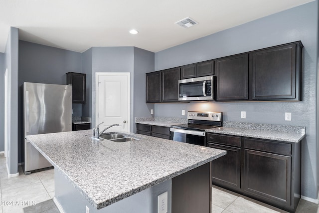 kitchen with sink, light tile patterned floors, a center island with sink, and appliances with stainless steel finishes