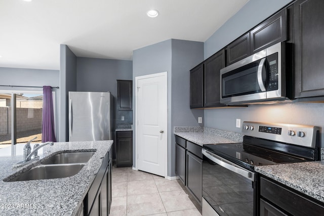 kitchen featuring light stone counters, stainless steel appliances, light tile patterned flooring, and sink