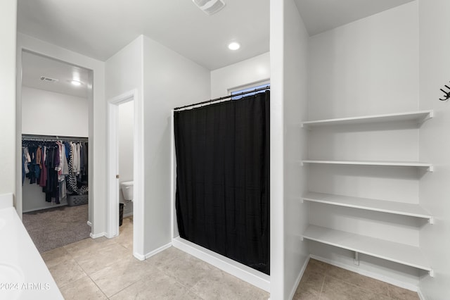 bathroom with tile patterned flooring, toilet, and walk in shower