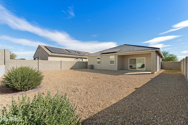 rear view of property with cooling unit, a patio, and solar panels