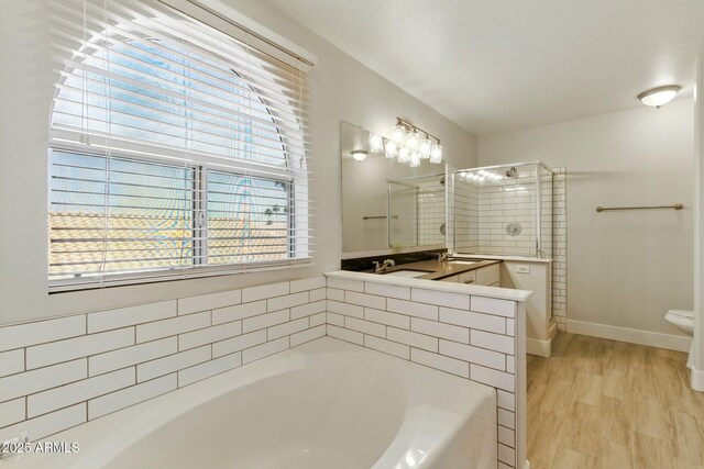 bathroom featuring a garden tub, a tile shower, baseboards, a sink, and toilet