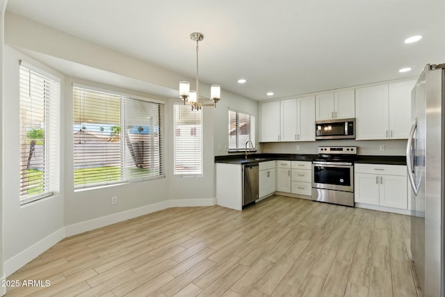 kitchen featuring stainless steel appliances, a sink, baseboards, healthy amount of natural light, and recessed lighting