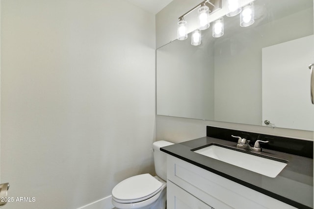 half bath featuring toilet, vanity, and baseboards