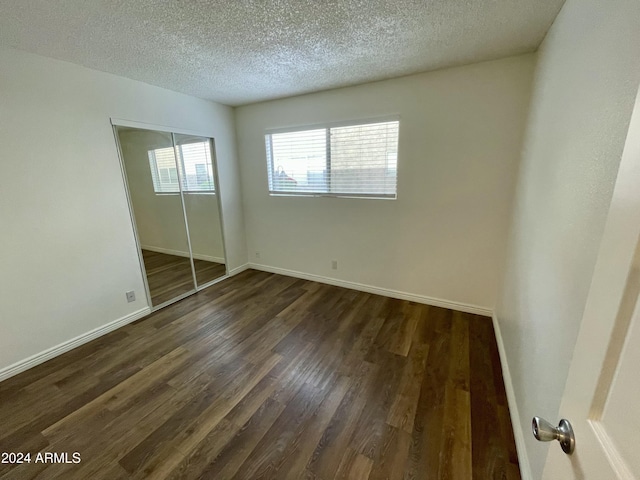 unfurnished bedroom featuring dark hardwood / wood-style flooring, a textured ceiling, and a closet