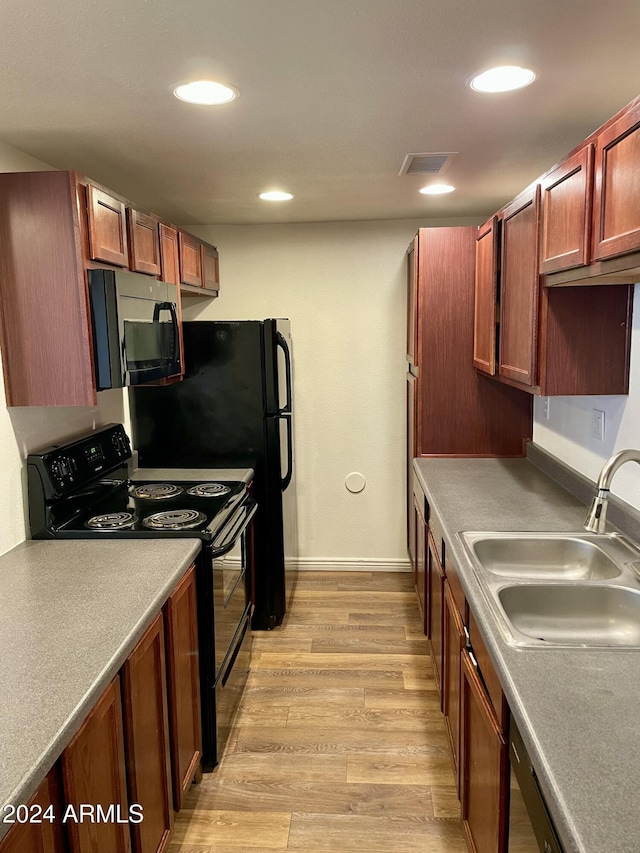 kitchen featuring electric range, light hardwood / wood-style flooring, and sink