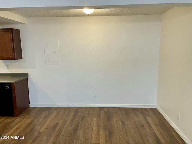 unfurnished dining area featuring a textured ceiling, dark wood-type flooring, and electric panel