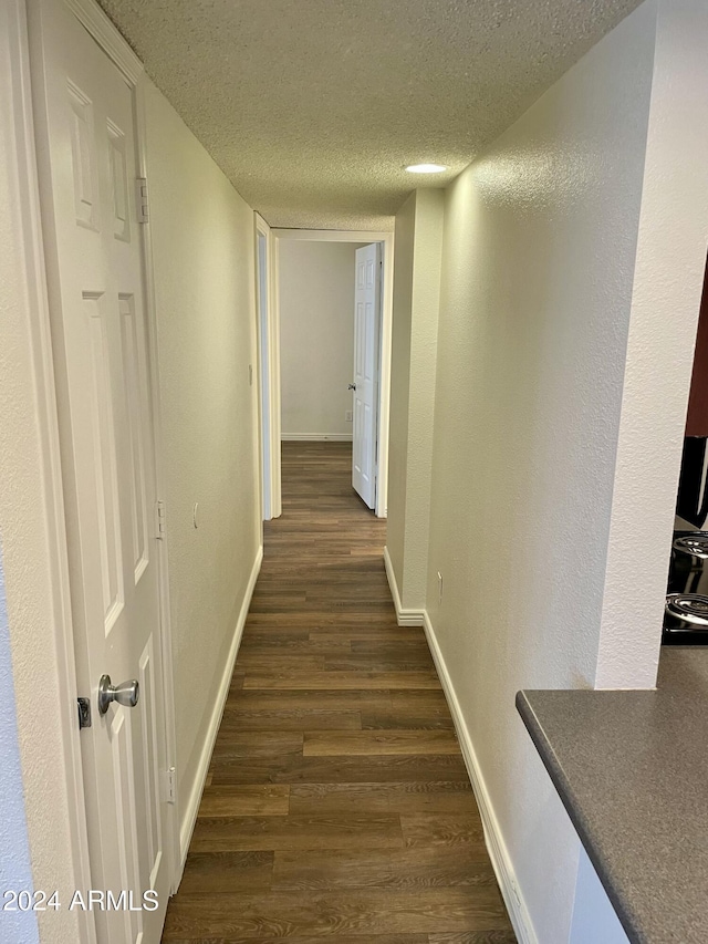 hallway featuring a textured ceiling and dark wood-type flooring