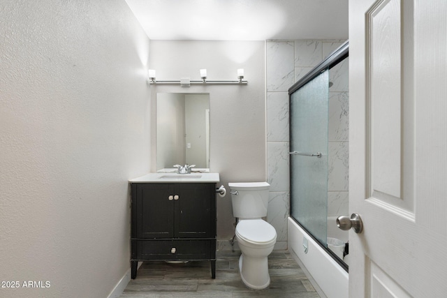 full bathroom featuring wood-type flooring, vanity, enclosed tub / shower combo, and toilet