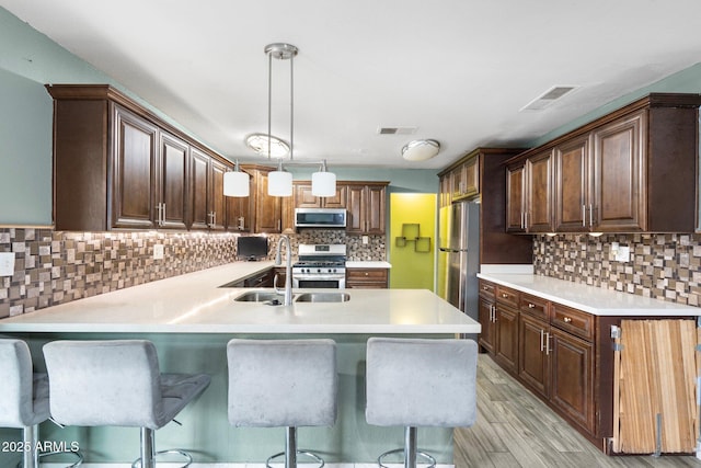 kitchen featuring pendant lighting, sink, stainless steel appliances, and a breakfast bar area