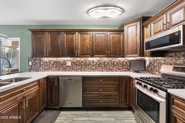 kitchen featuring decorative backsplash, dark brown cabinetry, sink, and appliances with stainless steel finishes