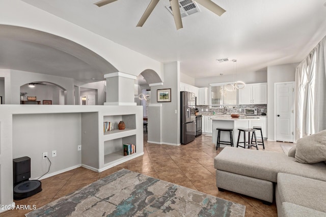 13420 W Berridge Ln, Litchfield Park, AZ 85340 - living room featuring a ceiling fan, light tile patterned floors, arched walkways, and baseboards