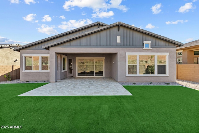 rear view of property with a yard, fence, stucco siding, and a patio